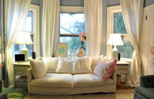 белый диван и шторы в интерьере гостиной с эркером