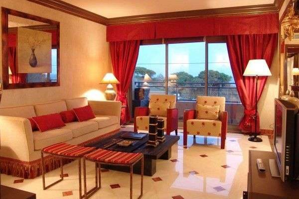 красные тяжёлые шторы в интерьере гостиной с бежевой мебелью