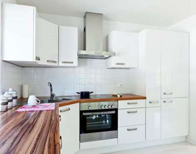 белая угловая кухня с деревянной столешницей